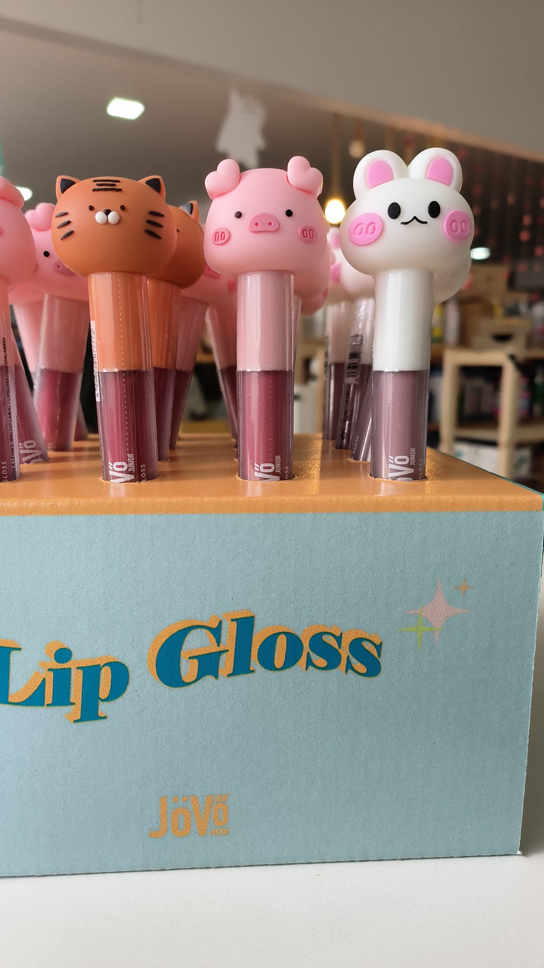Exibição de expositor com vários Lip Gloss Animais da JoVo, mostrando os designs de tigre, porco e coelho em tons de rosa e laranja.