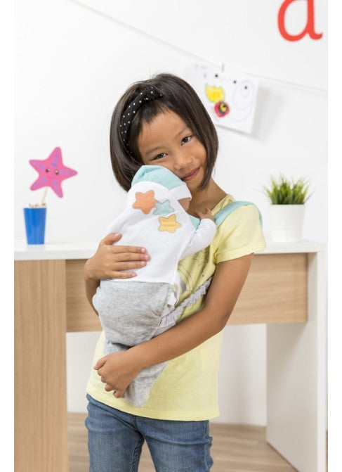 Criança sorridente a segurar um boneco Miniland vestido com o porta bebés, demonstrando como o acessório é usado em brincadeiras de imitação.