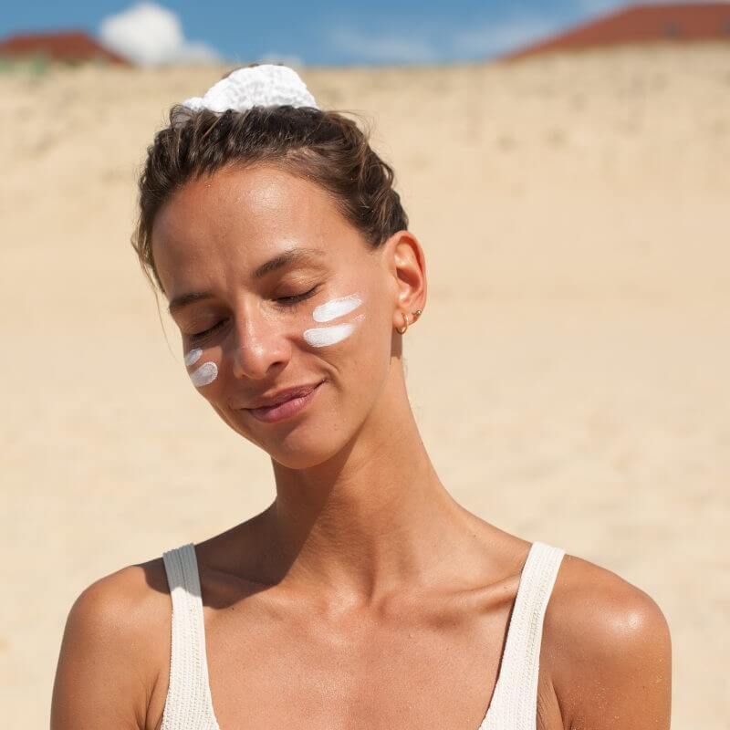 Mulher com protetor solar sólido Acorelle SPF50+ aplicado no rosto, protegendo a pele dos raios solares.