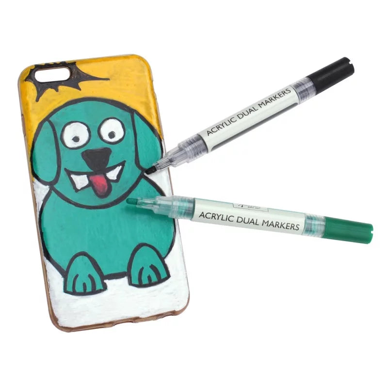 Dois marcadores acrílicos Nassau (preto e verde) pousados sobre uma capa de telemóvel personalizada com um desenho de cão, demonstrando a aplicação.