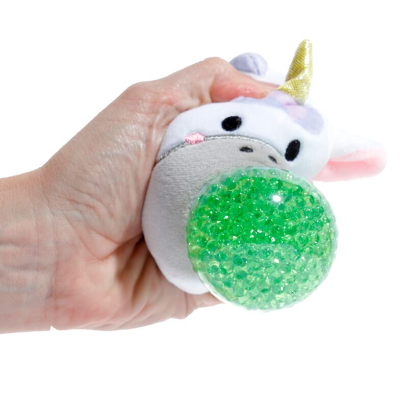 A hand squeezing an Adoramals Queasy Squeezies Unicorn plush toy, highlighting the green textured ball.