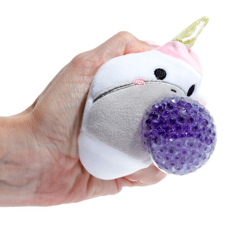 A hand squeezing an Adoramals Queasy Squeezies Unicorn plush toy, highlighting the purple textured ball.