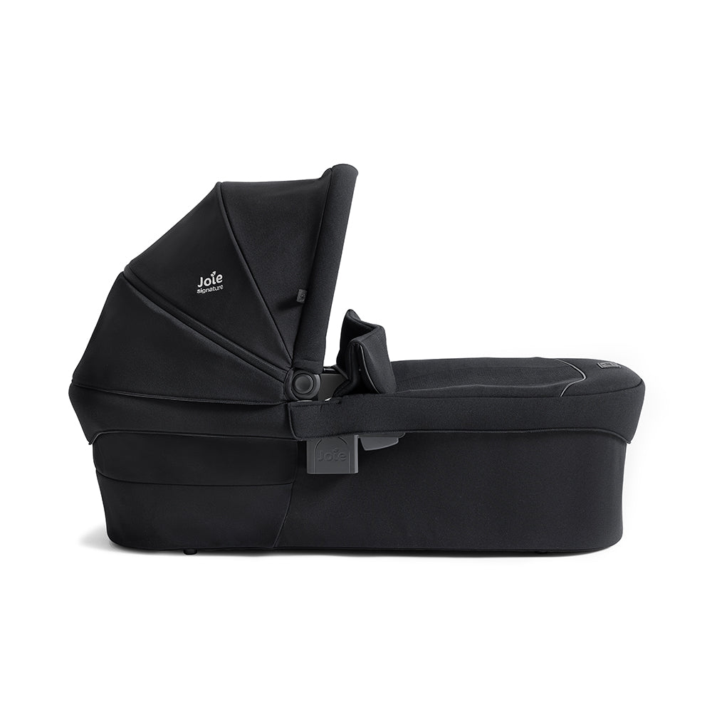 Alcofa Joie Ramble XL cinzenta escura, vista lateral, mostrando o design aconchegante e a alça de transporte em pele sintética.