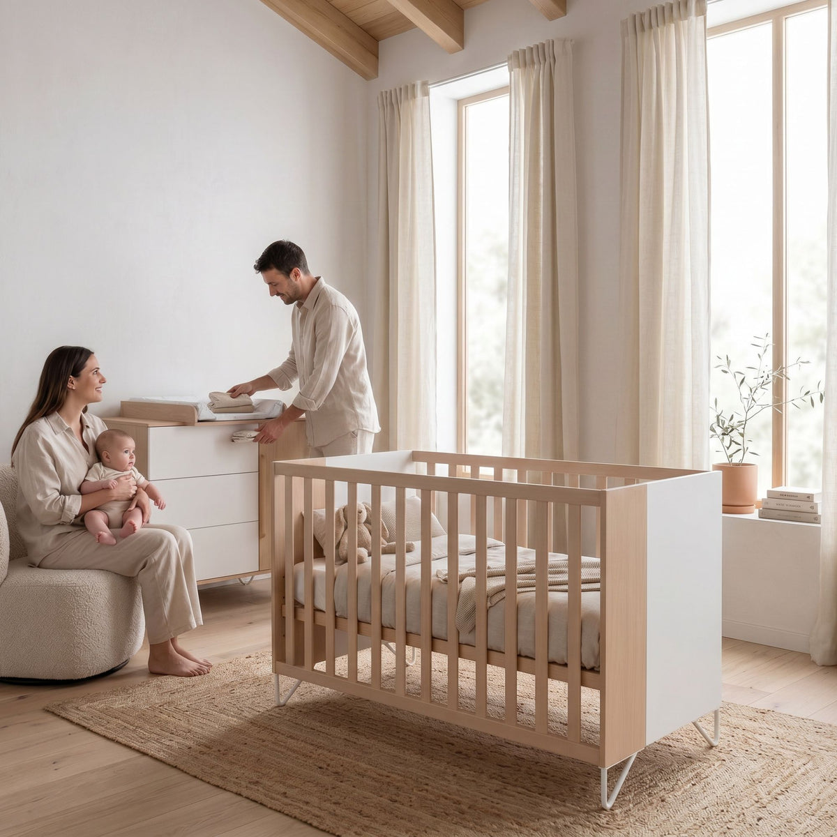 Micuna Amaia Berço 120x60 em Madeira / Branco num quarto de bebé luminoso, com os pais e o bebé ao lado do berço.