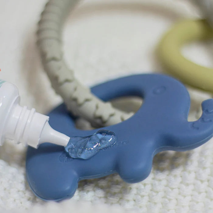 Detalhe do mordedor de elefante azul a receber a aplicação de um gel refrescante através de um aplicador de ponta fina.