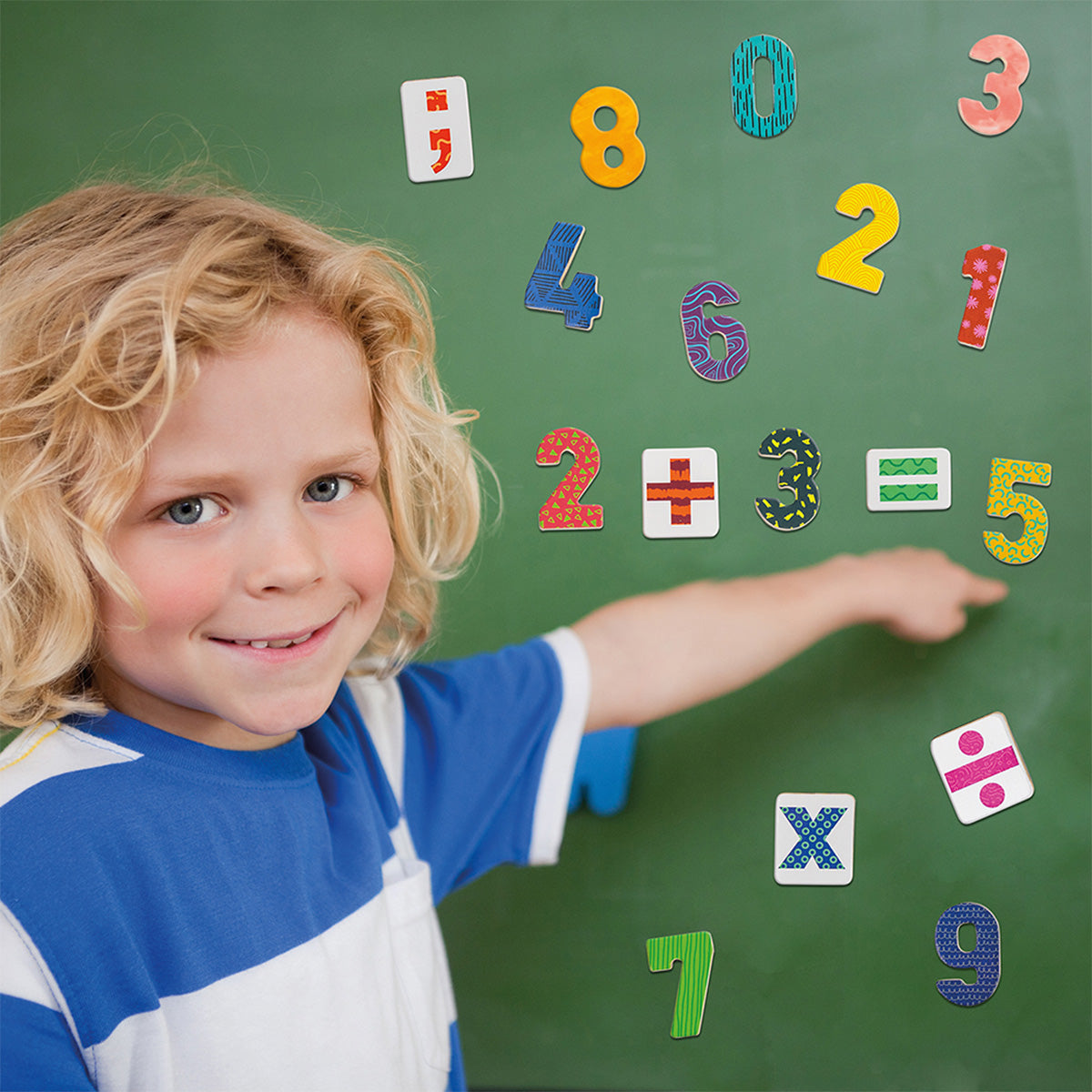 Criança sorrindo enquanto interage com os números magnéticos AS num quadro, aprendendo matemática de forma divertida.