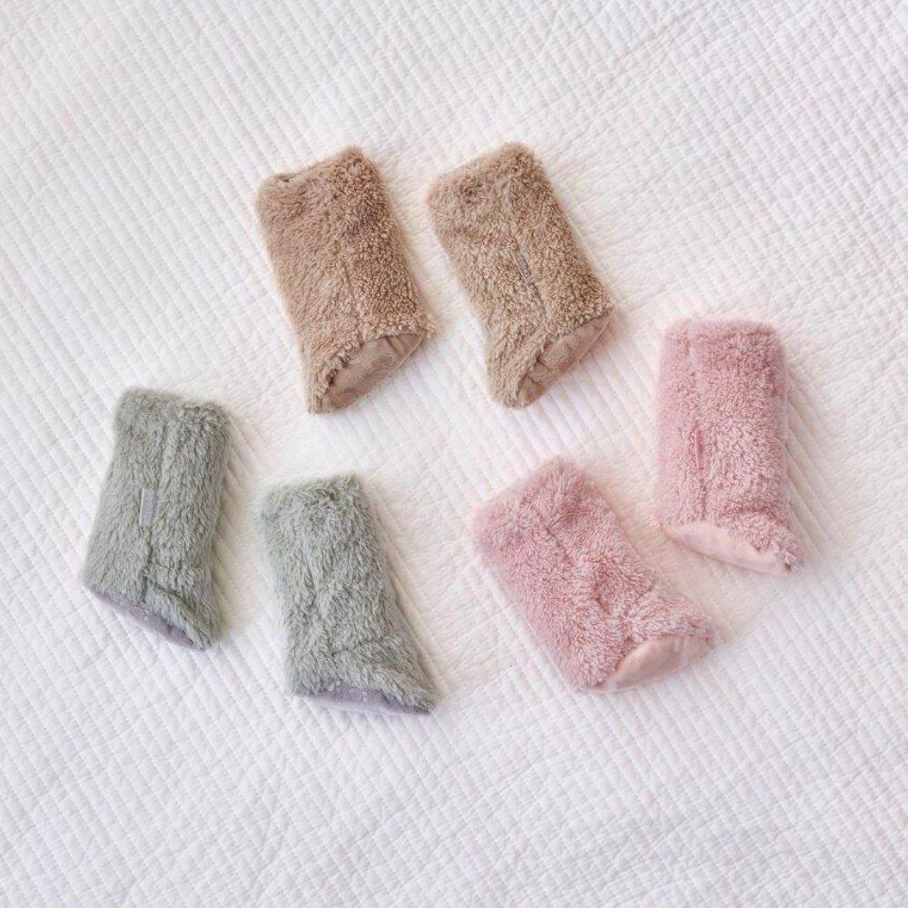 Conjunto de 6 aquecedores de pés Attipas em cores variadas (rosa, verde-acinzentado, bege) dispostos sobre um fundo branco acolchoado.