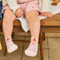 Criança sentada com as pernas a balançar, a usar os sapatinhos Attipas FAIRY PINK cor-de-rosa, mostrando o conforto e o design no pé.