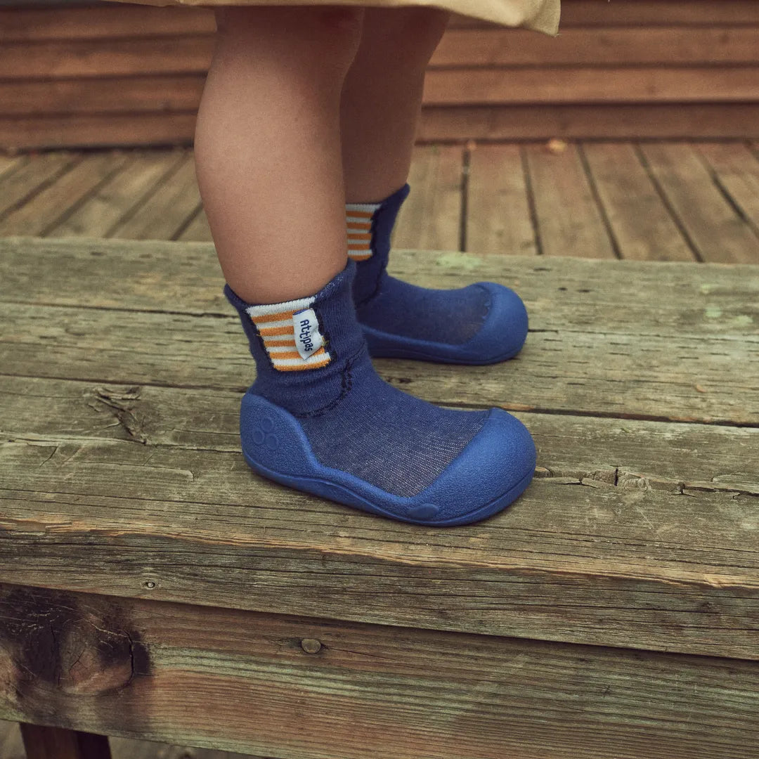 Close-up de um bebé com as Attipas Rain Boots Blue nos pés, destacando a flexibilidade da biqueira larga e o design respeitador do desenvolvimento natural do pé.