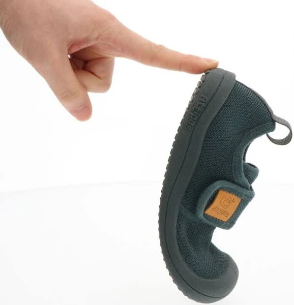 Demonstração da extrema flexibilidade da sola do sapato Attipas Skin Shoes verde escuro, dobrado pela pressão de um dedo humano.