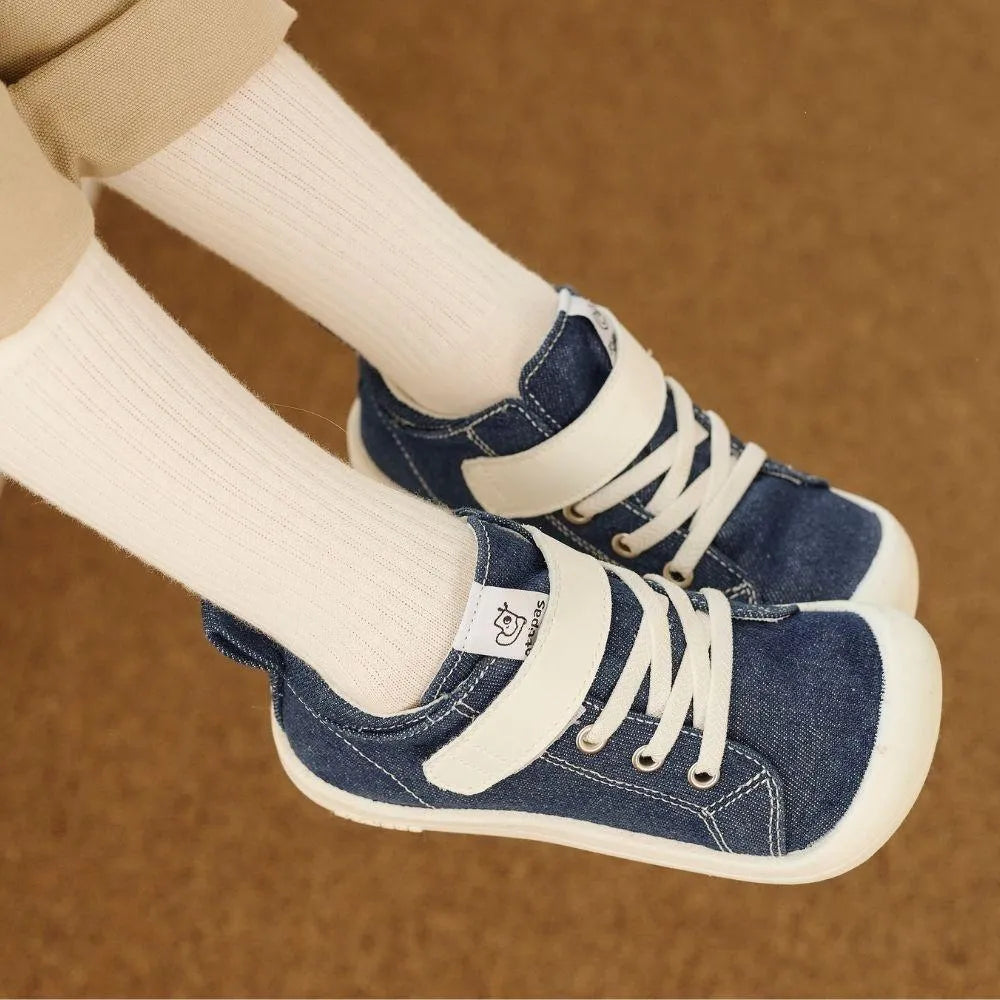 Criança a usar os Attipas Skin Shoes Denim Azul com meias brancas, evidenciando a flexibilidade da sola e o conforto do calçado respeitador.