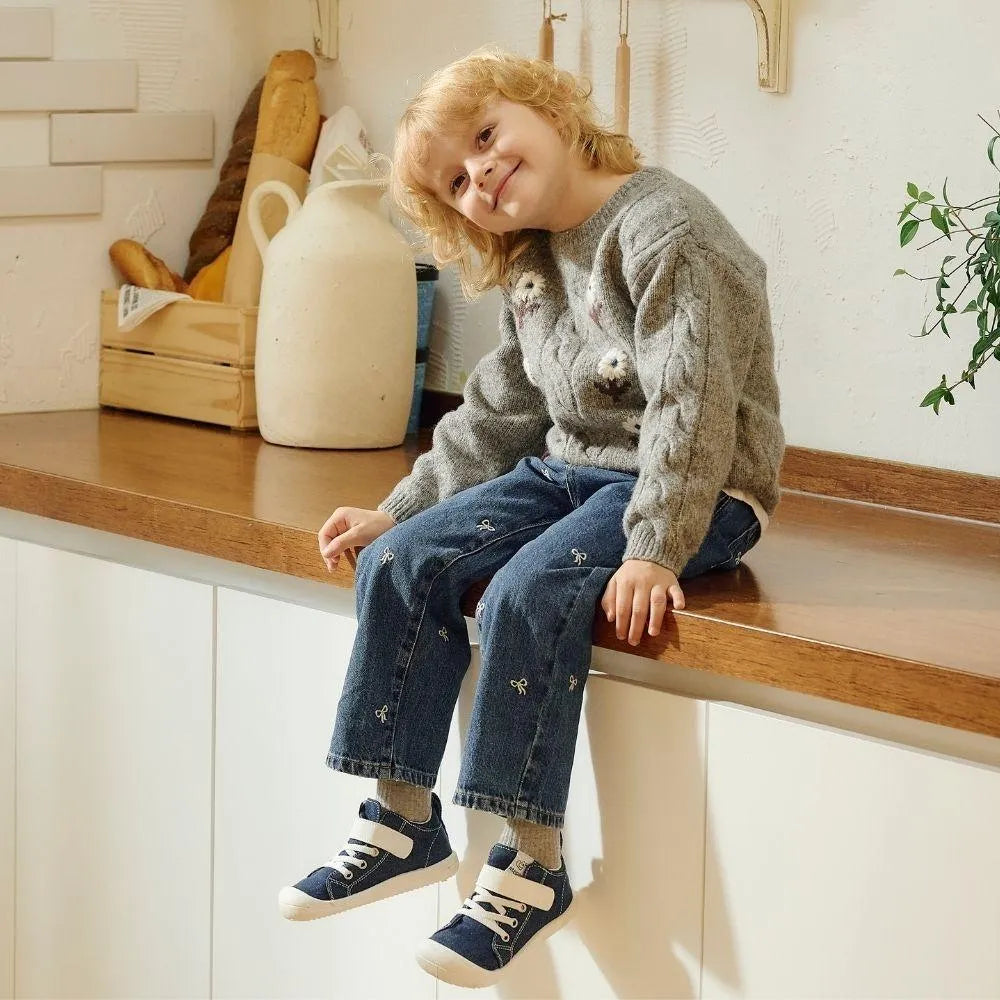 Menino sentado num balcão com os Attipas Skin Shoes Denim Azul nos pés, combinando conforto e estilo num calçado barefoot ergonómico.