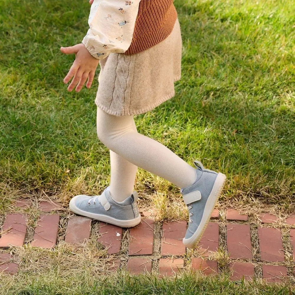 Menina a andar sobre um caminho de tijolos, usando os Attipas Skin Shoes Denim Light Blue, mostrando o ajuste perfeito e o conforto do calçado barefoot.