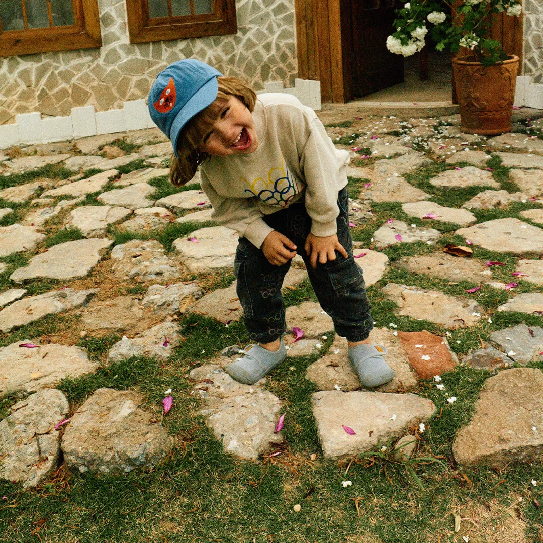 Criança a saltar pedras com Attipas Skin Shoes (Grey), mostrando a estabilidade e a aderência do calçado durante brincadeiras ativas.
