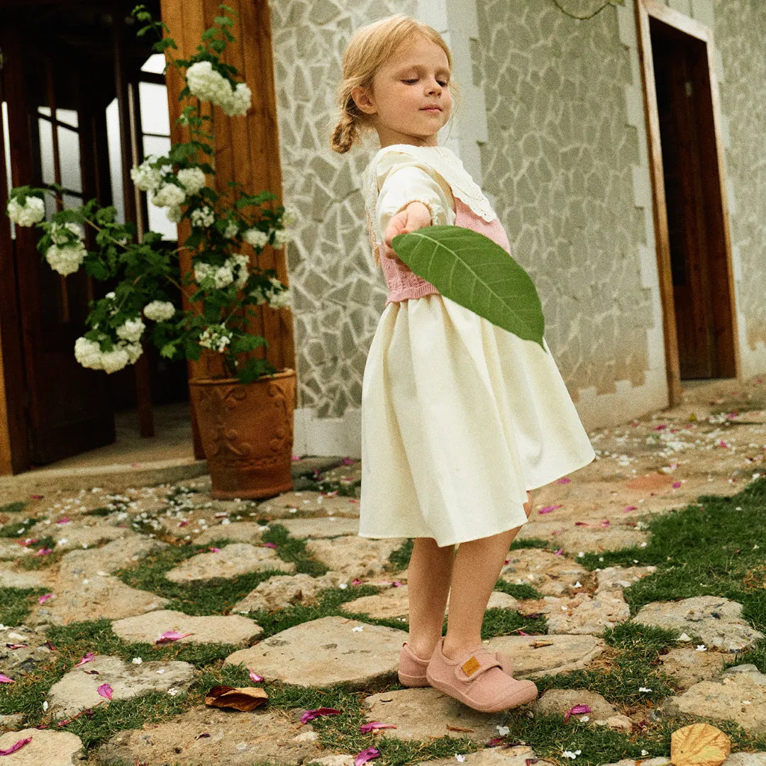 Menina segurando uma folha enquanto usa Attipas Skin Shoes Pink, reforçando o conceito de um calçado respeitador, ideal para todas as aventuras infantis.
