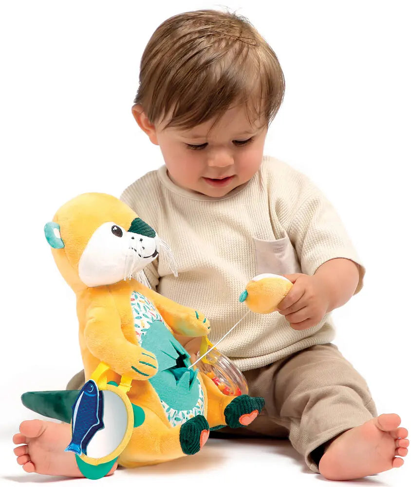 Um bebé sentado no chão a brincar com o brinquedo Ludi Lontra com atividades, segurando um dos elementos destacáveis da lontra.