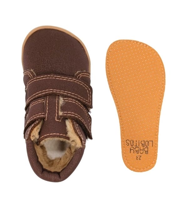 Vista superior da bota infantil Baby Lobitos Eclipse castanha com fecho de velcro e interior de pêlo, ao lado da palmilha removível laranja.