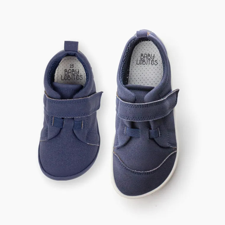 Par de Baby Lobitos Barefoot Deportivas Compás - Nova Sola, sapatilhas infantis barefoot azul colegial com sola azul flexível. Leves, confortáveis e vegan.