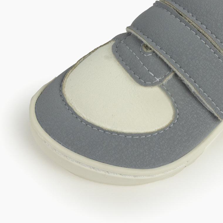 Close-up da biqueira das sapatilhas Baby Lobitos, realçando o material cinzento texturizado e a secção clara da frente.