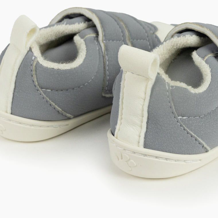 Detalhe das traseiras das sapatilhas Baby Lobitos cinzentas, focando no puxador branco e na sola fina com marca de pata.
