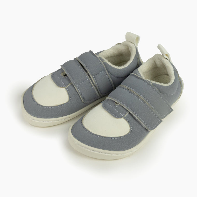 Par de sapatilhas Baby Lobitos Barefoot cinzentas (ceniza) com fecho de velcro duplo, forro branco e biqueira clara, em fundo branco.