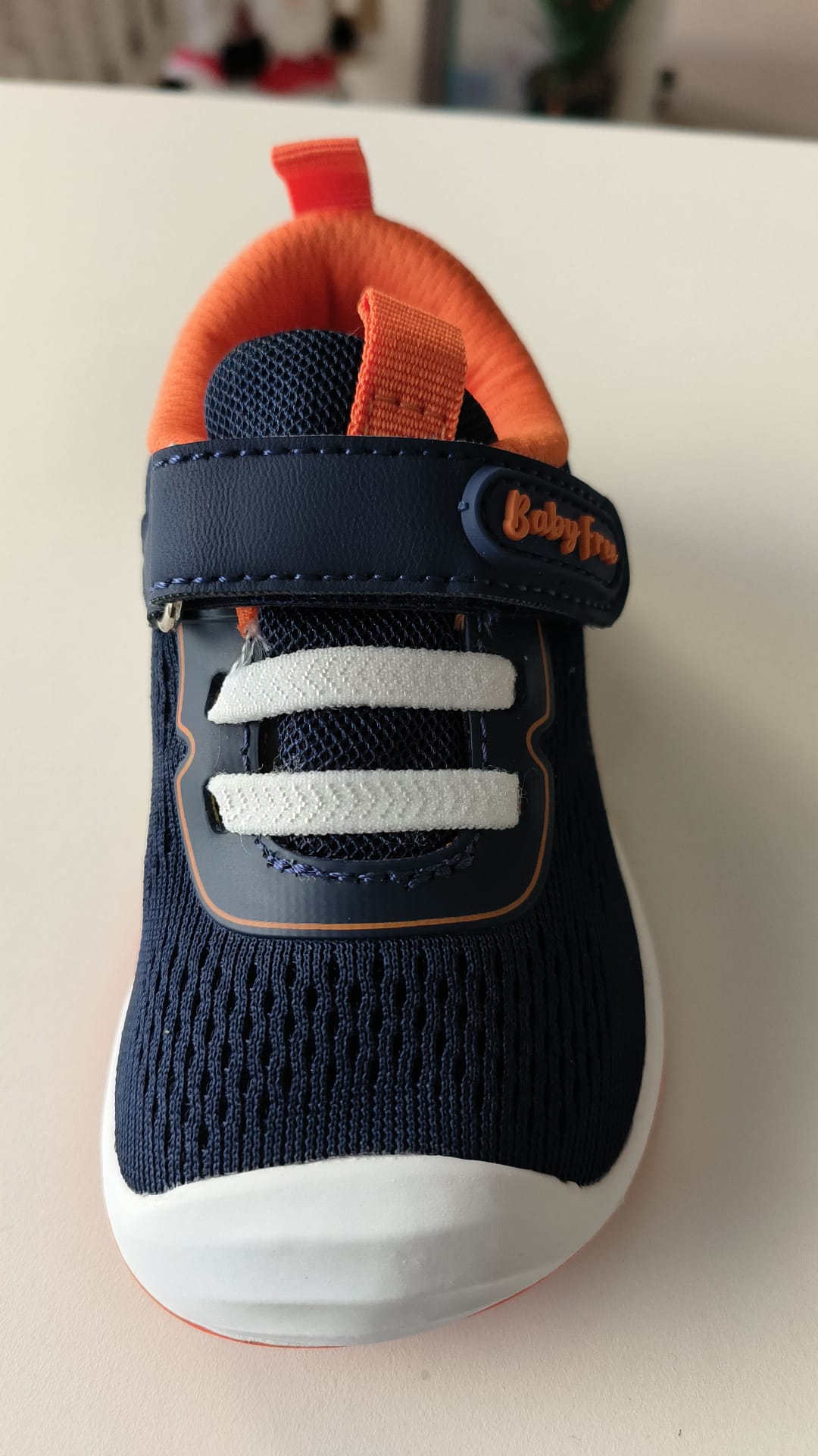 Vista frontal da sapatilha Chetto BabyFree azul-marinho, mostrando a ponta ampla, os elásticos decorativos e a tira de velcro com o logótipo.