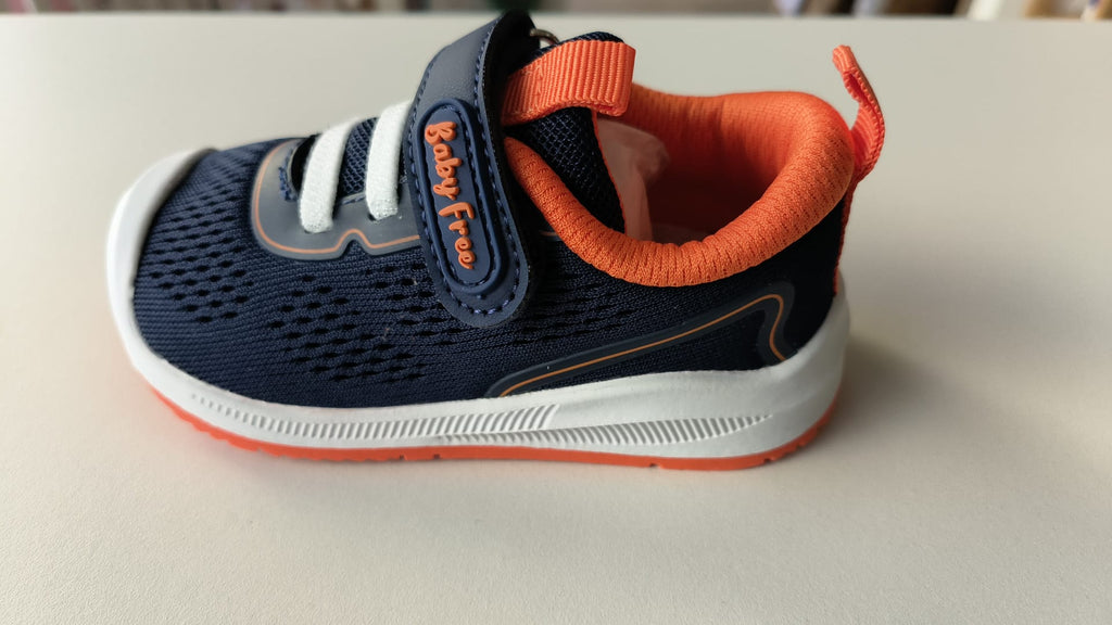 Imagem lateral da sapatilha Chetto BabyFree azul-marinho e laranja, mostrando o design leve, a malha respirável e o fecho de velcro.