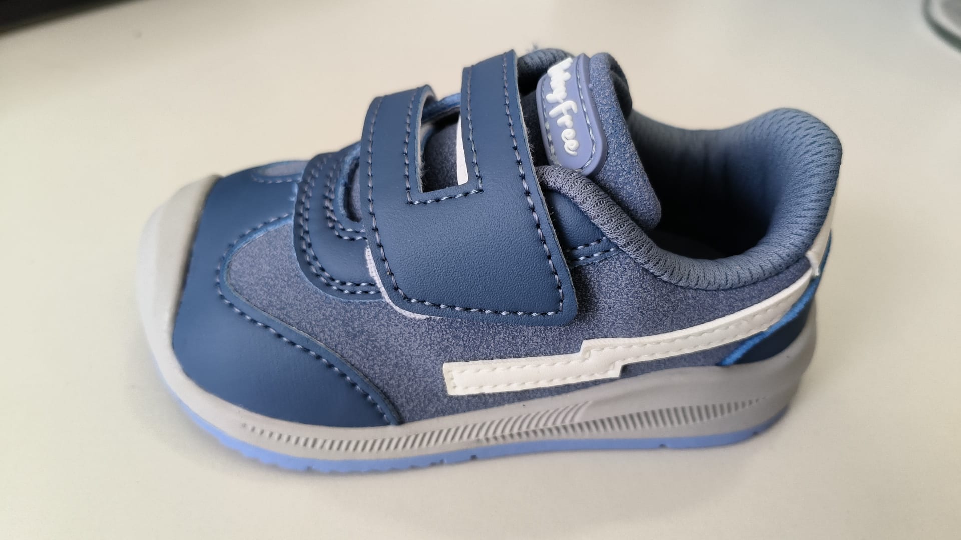 Sapatilha barefoot BabyFree azul de criança, vista lateralmente, com fecho de velcro duplo e detalhes em cinzento claro.