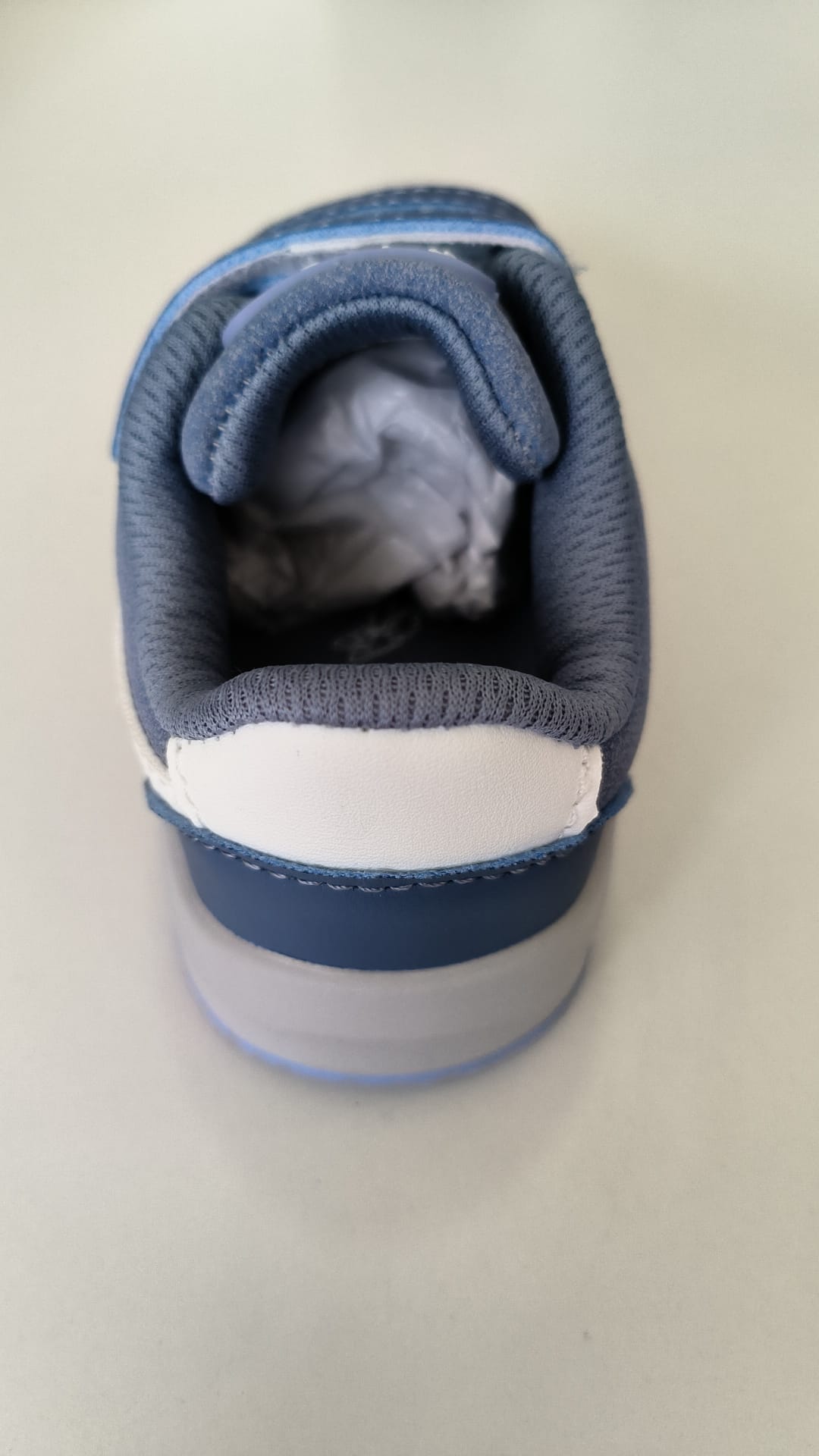 Vista traseira da abertura da sapatilha barefoot azul, mostrando o interior acolchoado e a zona do calcanhar.