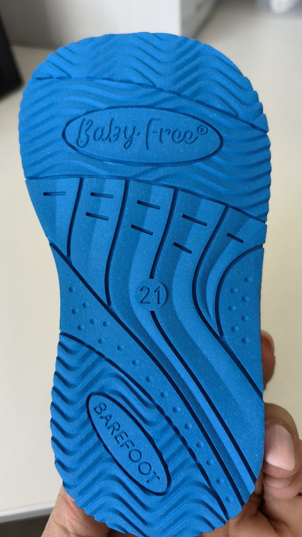 Sola azul da sapatilha BabyFree Barefoot, mostrando o relevo antiderrapante, a inscrição "Baby Free" e o tamanho "21".