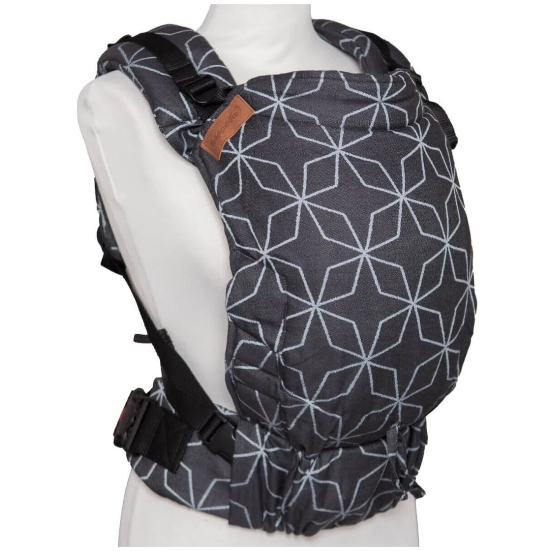 Imagem de uma Mochila Hoppediz Ajustável BabySize Buckle em padrão geométrico de linhas brancas sobre fundo cinza escuro. A mochila está exibida em um manequim branco, mostrando o seu design ergonómico, alças acolchoadas e ajustáveis, bem como o painel traseiro que se adapta ao corpo do bebé. O material parece confortável e resistente, adequado para transporte seguro e prático de bebés.