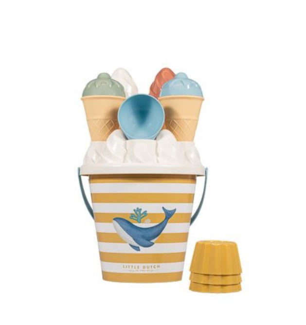 Balde de praia Ocean Dreams listrado em amarelo e branco, com a tampa cheia de moldes de gelado e uma colher azul, e moldes extra ao lado.