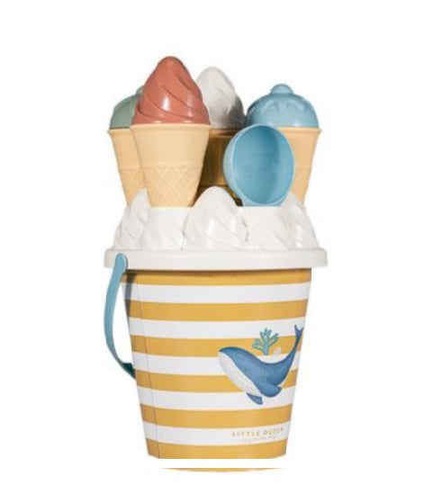 Imagem de estúdio do balde de praia Little Dutch Ocean Dreams amarelo e branco, com a baleia, cheio de moldes de gelado coloridos e uma colher azul.