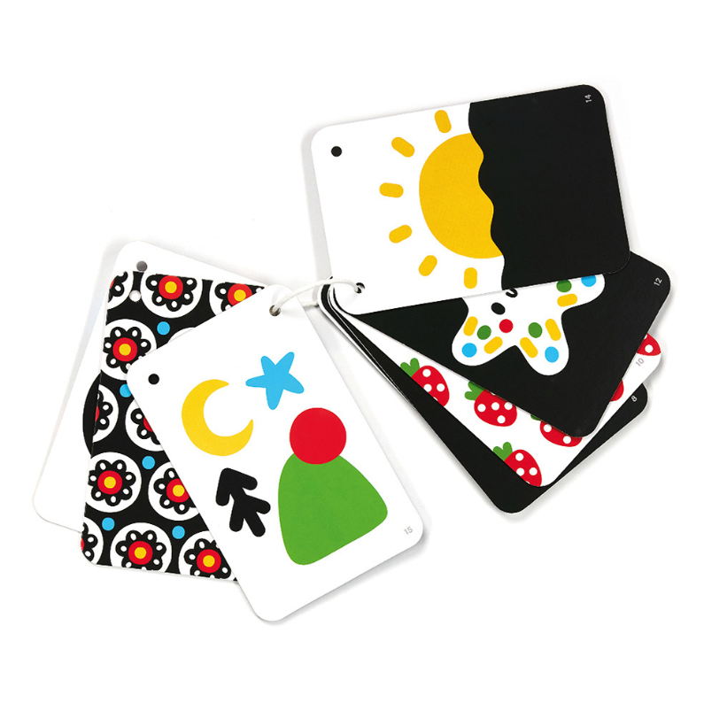 Vários cartões de alto contraste da Banana Panda abertos, mostrando ilustrações variadas como um sol, lua, estrelas e padrões florais, presos por um pequeno cordão.