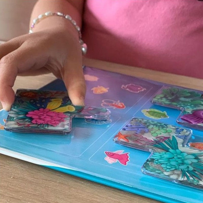 Uma criança a colocar uma peça de quebra-cabeças magnética com um coral colorido no tabuleiro azul do jogo Recife de Coral.