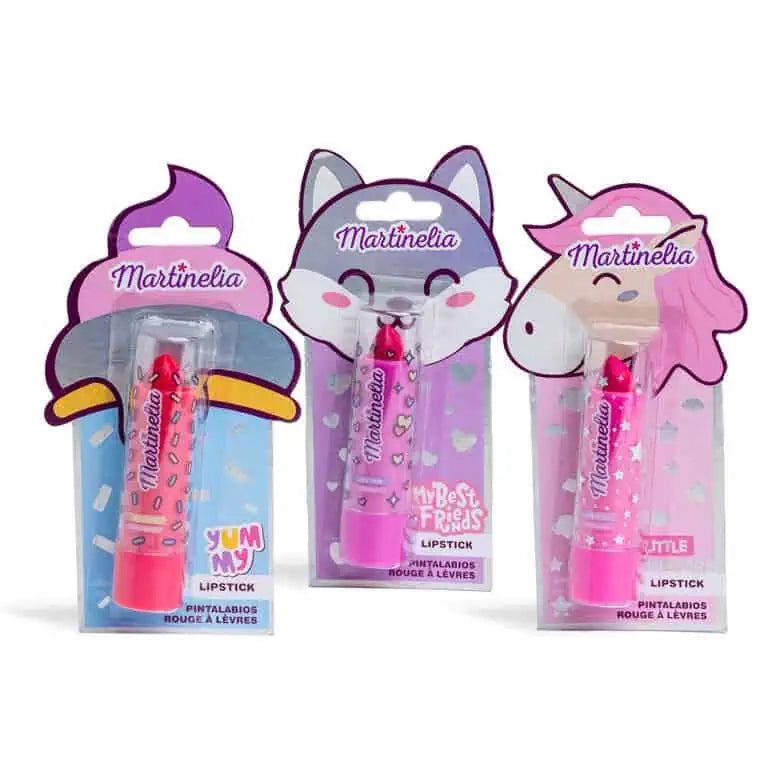Três batons Martinelia infantis lado a lado: Yummy (vermelho/laranja), My Best Friends (rosa/corações) e Little Unicorn (rosa/estrelas), em embalagens temáticas.