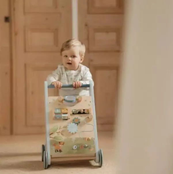 Bebé a utilizar o andarilho de atividades Little Dutch, empurrando-o com as duas mãos enquanto sorri.