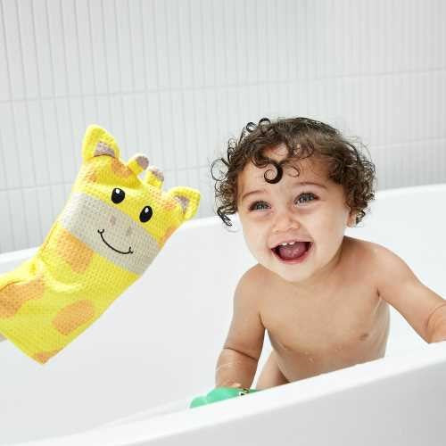Bebé feliz na banheira a brincar com a luva de banho amarela em forma de girafa da Dock & Bay.