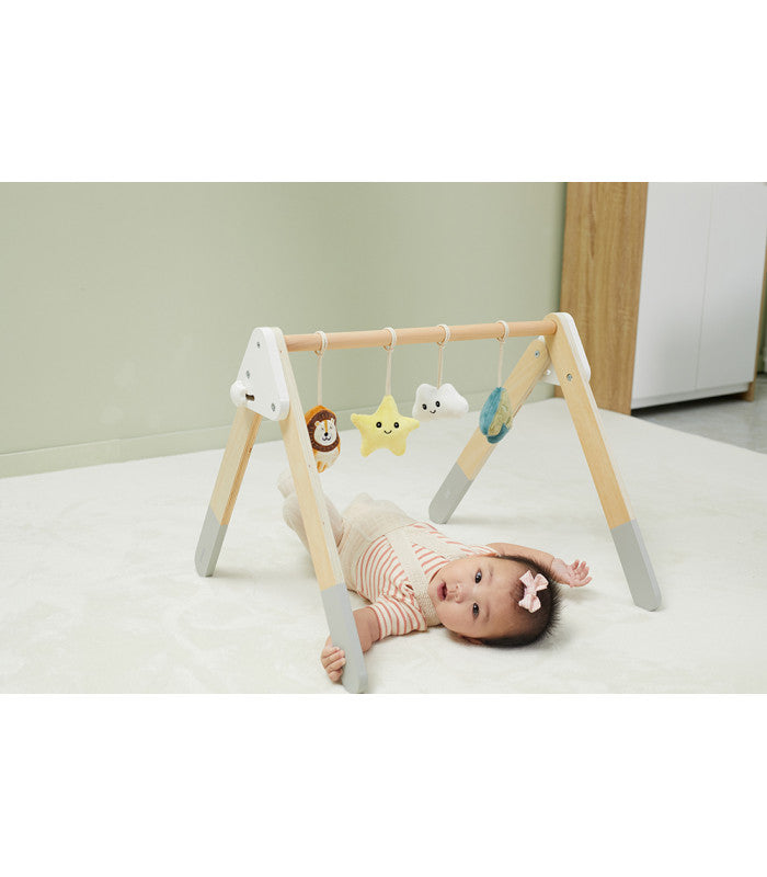 Bebé feliz a brincar com o ginásio de atividades PolarB, interagindo com os brinquedos pendurados.