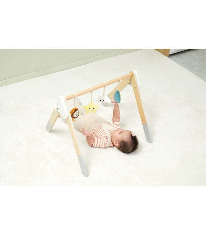 Outro ângulo do bebé a brincar com o ginásio de atividades PolarB, mostrando a interação com os brinquedos.