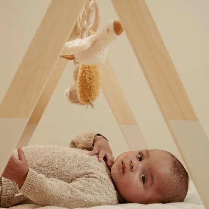 Bebé deitado sob o ginásio de atividades Little Dutch, com a mão levantada a tentar alcançar o brinquedo em forma de pato branco.