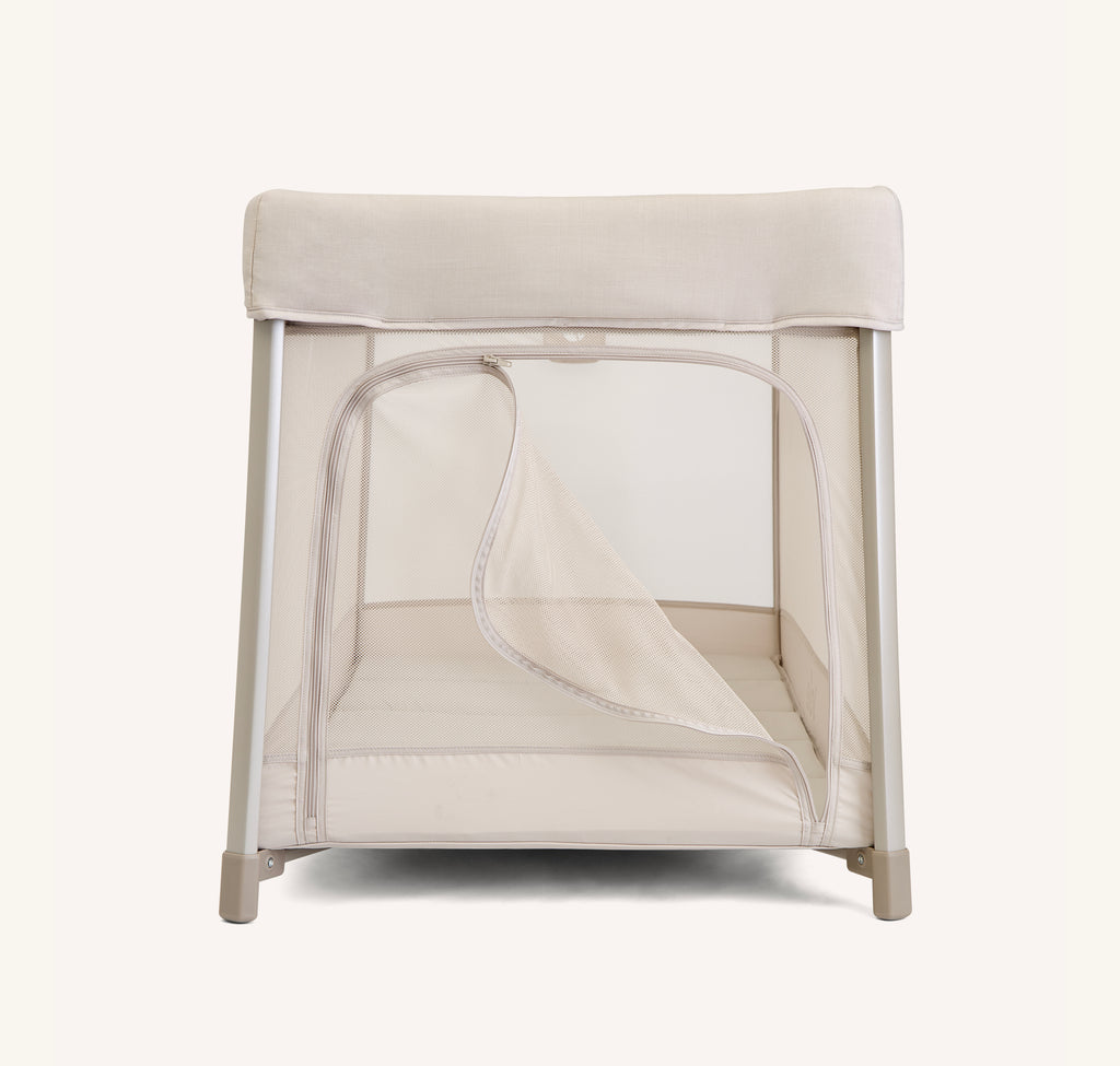 Vista lateral do berço de viagem Joie amigo™ 120, mostrando a abertura do zíper lateral que serve de porta de acesso.