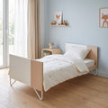 Micuna Big Amaia Berço 140x70 em Madeira / Branco convertido em cama pequena, num quarto com parede azul.