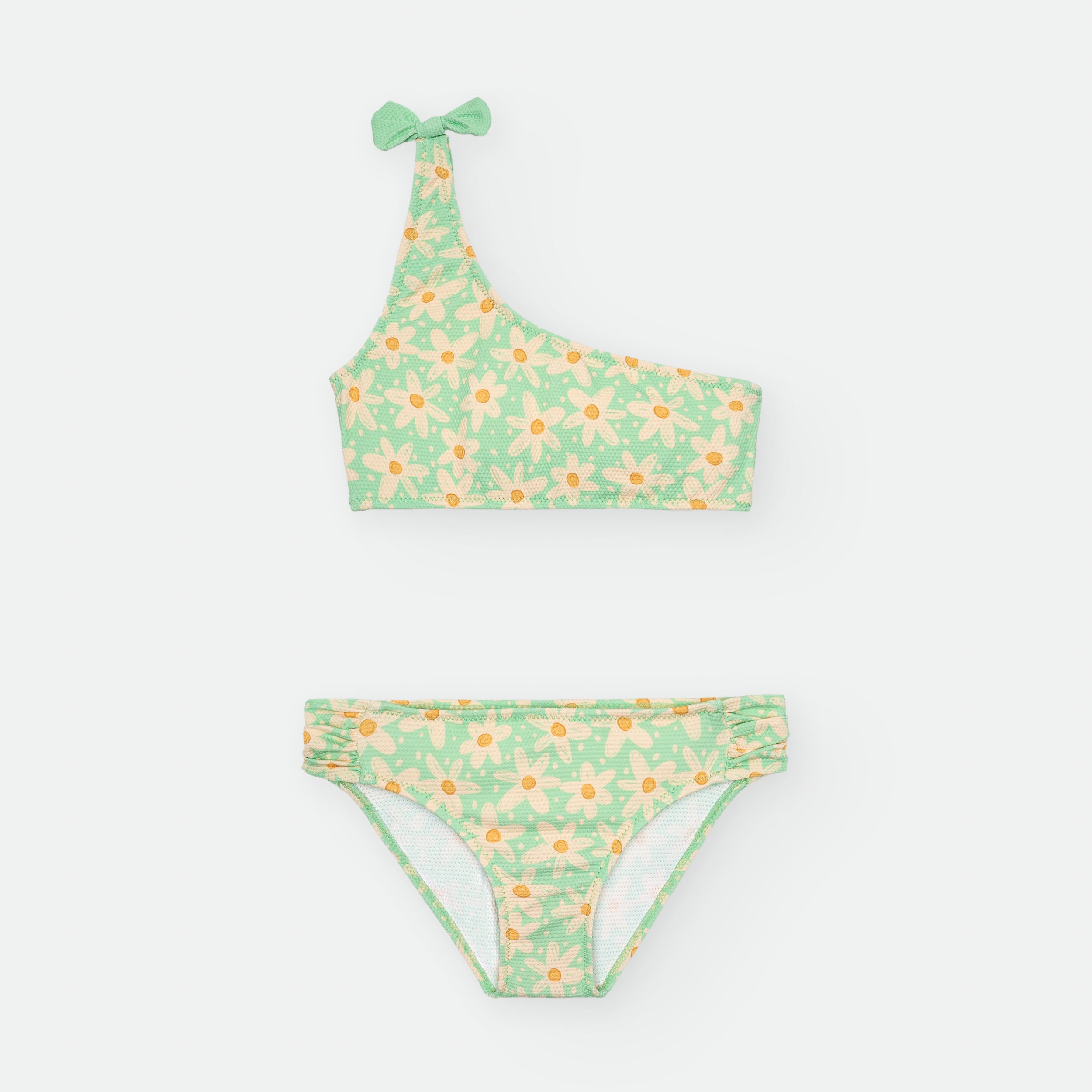 Biquini infantil asimetrico da Waterlemon com padrao de margaridas sobre fundo verde pastel para menina.