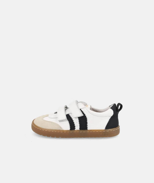 Sapatilha infantil Barefoot Blanditos Delfin (Branco/Preto) em vista lateral, mostrando o design desportivo com riscas pretas e biqueira bege.