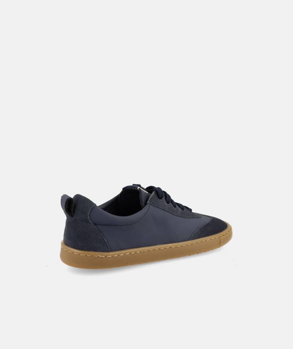 Detalhe da parte de trás da sapatilha barefoot Blanditos Delfin marinho, mostrando o tecido, o puxador do calcanhar e a sola de borracha.