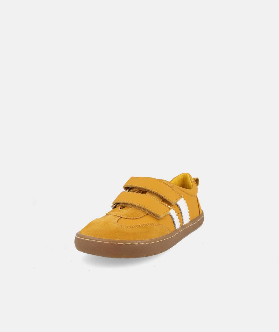 Sapatilha infantil Barefoot Blanditos Delfin cor ocre, vista frontal oblíqua, com fecho de duas tiras de velcro e riscas brancas laterais.