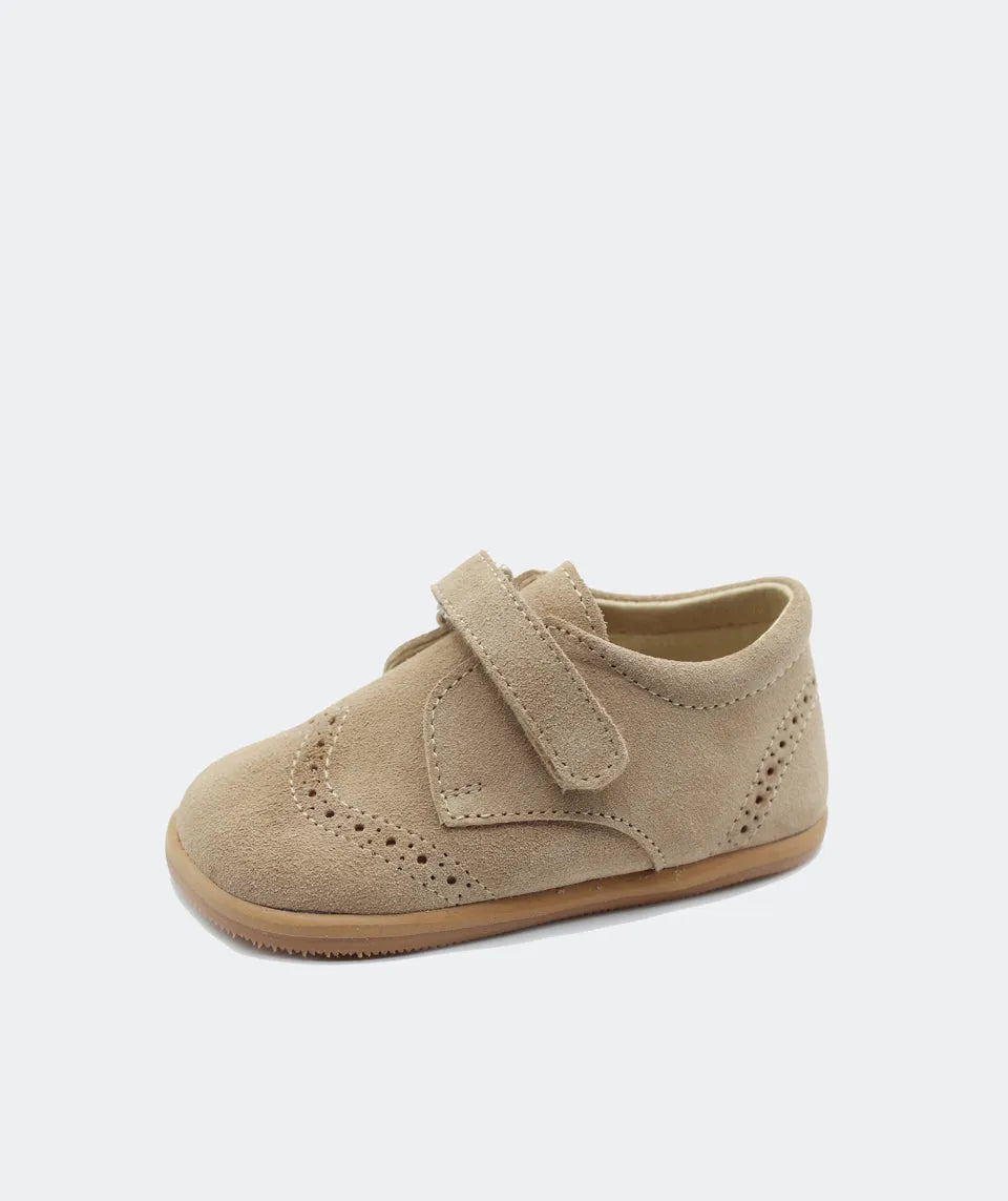 Blanditos by Crio’s Clássico Leo Arena em bege. Sapato de cerimónia com fecho em velcro, perfurações decorativas e sola em borracha natural, garantindo conforto e liberdade de movimento.