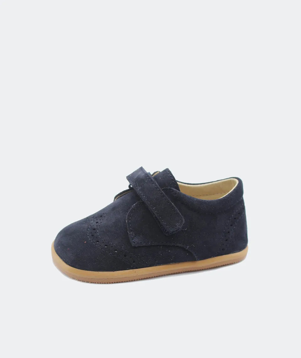 Blanditos by Crio’s Clássico Leo Navy em azul-marinho. Sapato de cerimónia com fecho em velcro, perfurações decorativas e sola em borracha natural, oferecendo elegância e conforto.