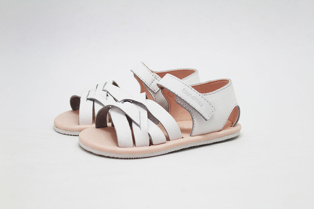 Par de sandálias abertas Blanditos by Crio's em pele branca, com palmilha rosa claro, sobre fundo branco.